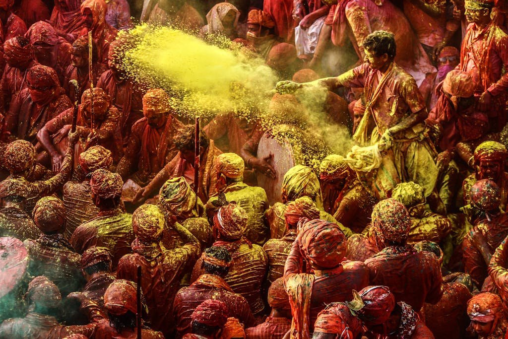 Crowd celebrating Holi festival with colorful powders in vibrant outdoor setting.