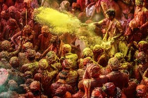 Crowd celebrating Holi festival with colorful powders in vibrant outdoor setting.